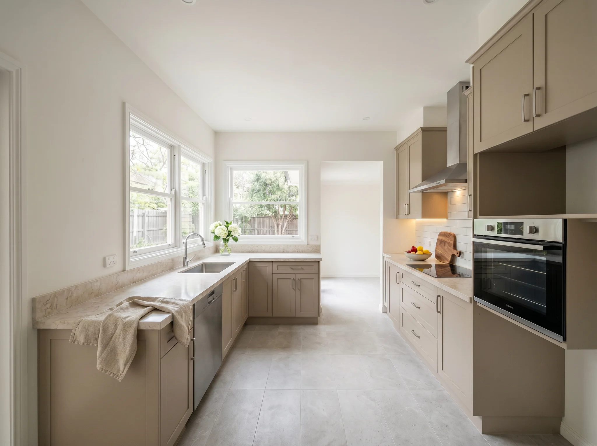 Taupe galley kitchen listing styling with flowers at sink, fruit bowl, and under-cabinet glow