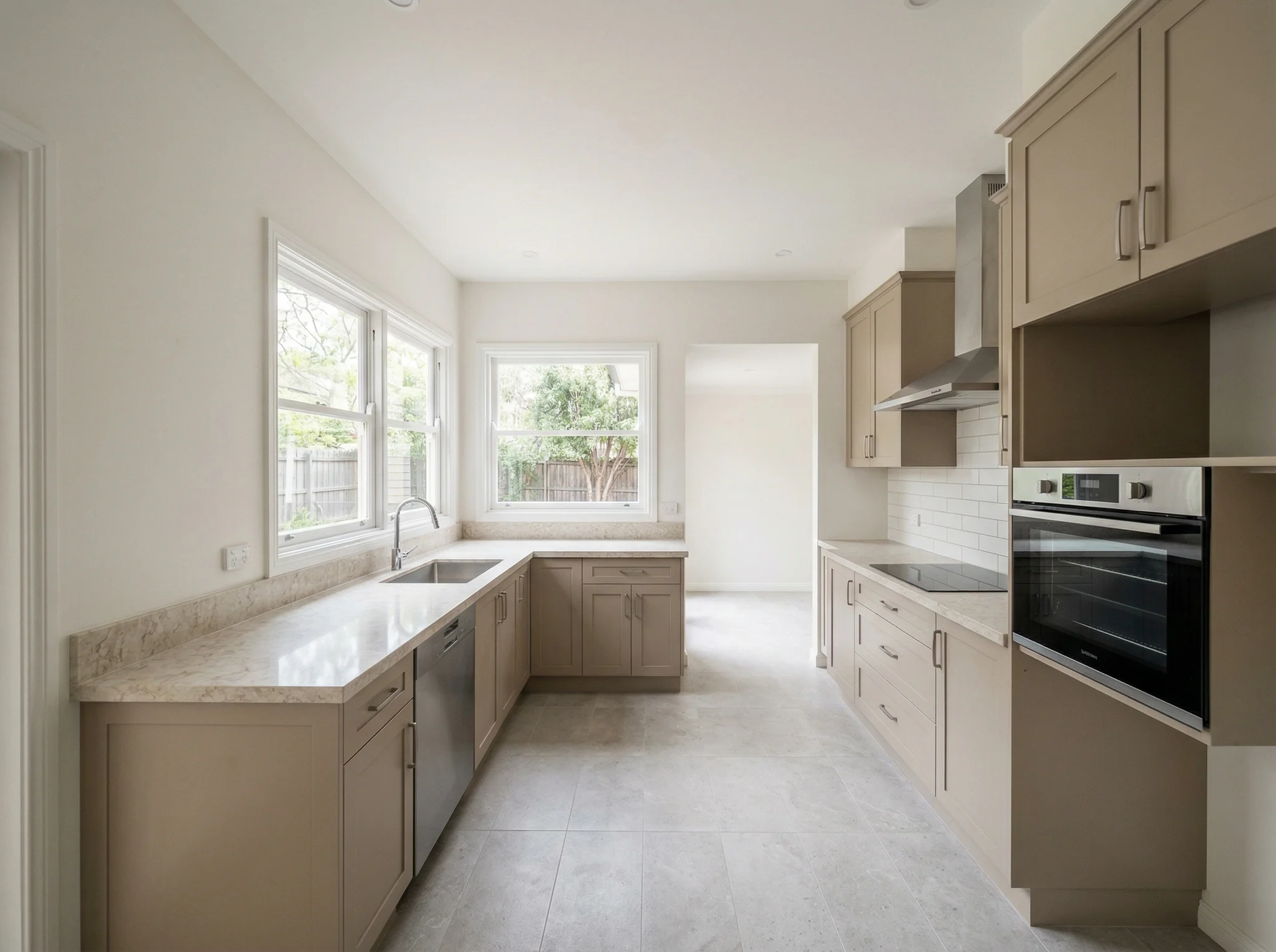 Taupe galley kitchen with two garden windows before listing-photo styling