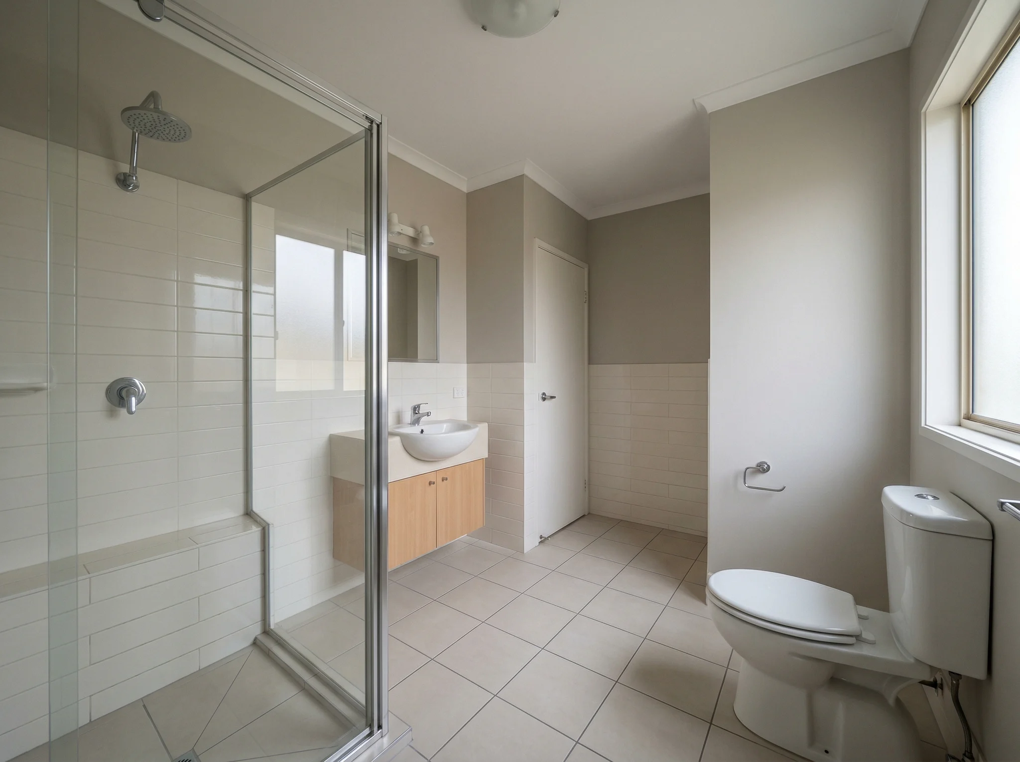 Plain bathroom with glass shower and bare vanity before guest-ready styling